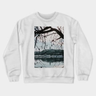 Branches of trees in front of church tower with river bank. Crewneck Sweatshirt